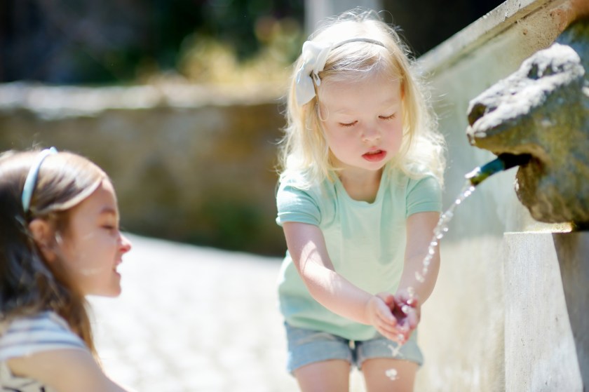 Two girls playing with drinking water fountain